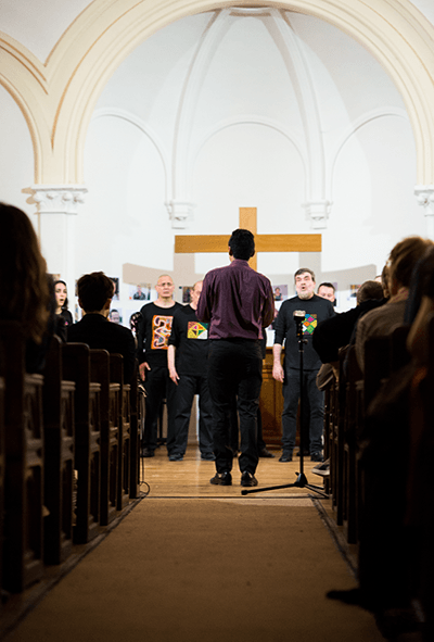 photo of a choirmaster directing his singers in a church