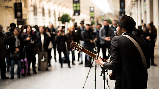 photo of a singer singing in front of a crowd in a train station