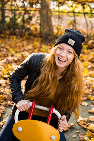 portrait of woman in a chlidren playground, she's sitting on a see-saw