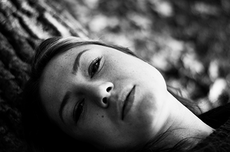 portrait of woman lying on a fallen tree, face close up, black & white